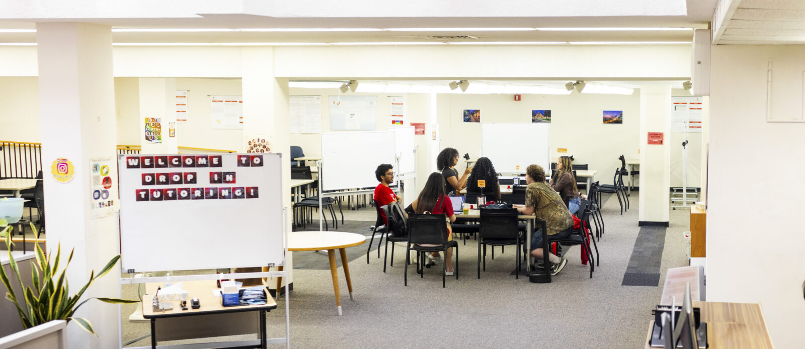 Six students are gathered at the drop-in tutoring tables at the Math Learning Center, receiving tutoring services.