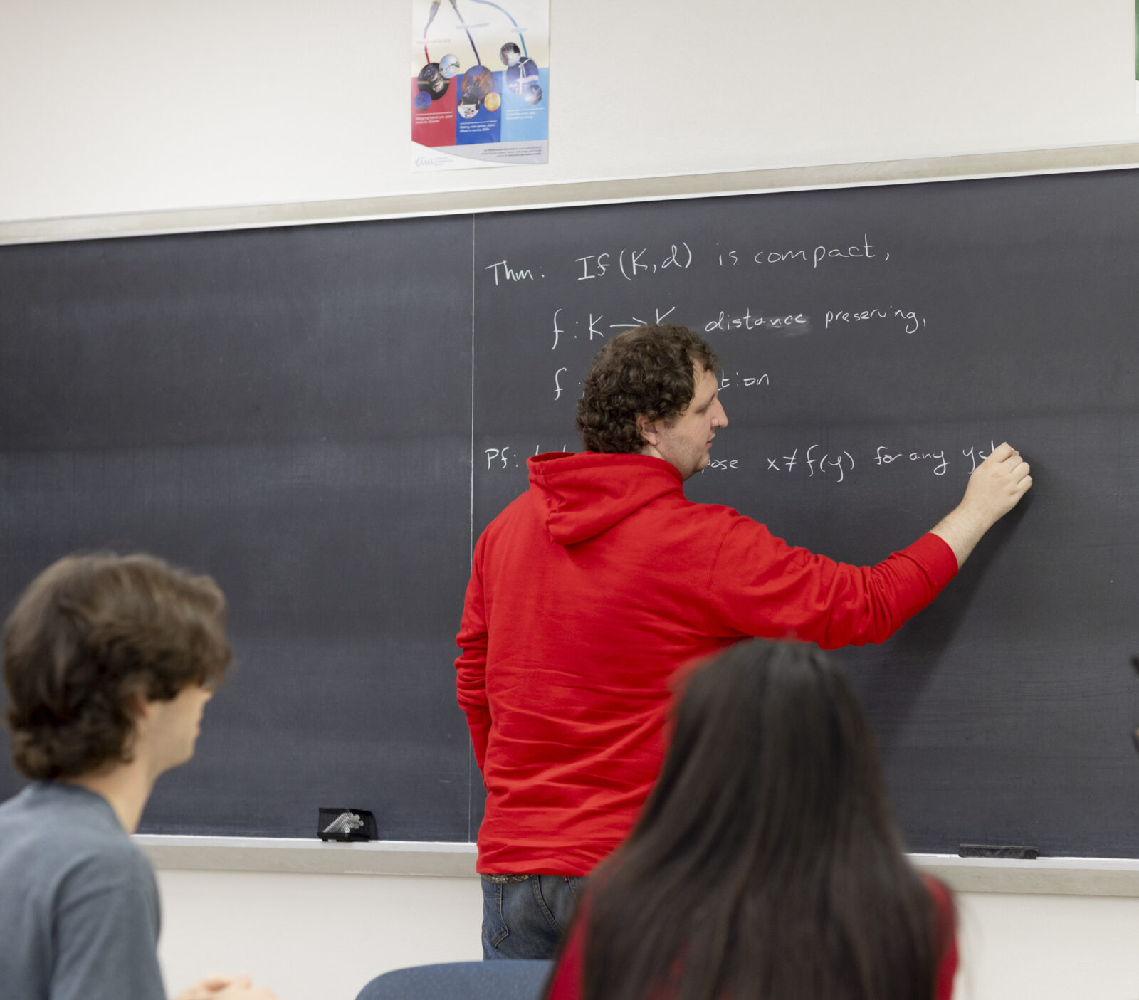 A student writes on a chalkboard in the Proof Table.